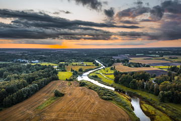 Aerial view on impressive thunderstorm over a countryside at sunset. Dark storm clouds covering the...