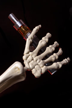 Skeleton hand holding an ecigarette with ejuice in it