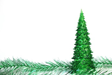 Green toy Christmas tree and tinsel are isolated on white background. Copy space.