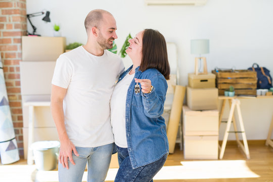 Young couple smiling very happy showing keys of new home, moving and buying new apartmet concept