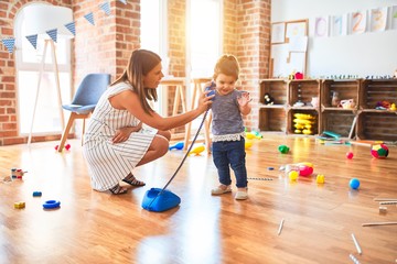 Young beautiful teacher and toddler playing with vintage phone at kindergarten