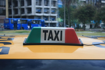 A sign in green white red with the word taxi writting in it on top of a car