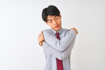 Chinese businessman wearing elegant tie standing over isolated white background Hugging oneself...