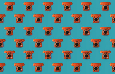 Seamless pattern of an orange retro style telephone, isolated on a blue background