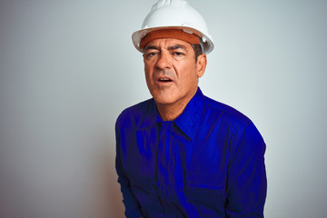 Handsome middle age worker man wearing uniform and helmet over isolated white background with hand on stomach because nausea, painful disease feeling unwell. Ache concept.