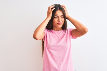 Young beautiful woman wearing pink casual t-shirt standing over isolated white background suffering from headache desperate and stressed because pain and migraine. Hands on head.