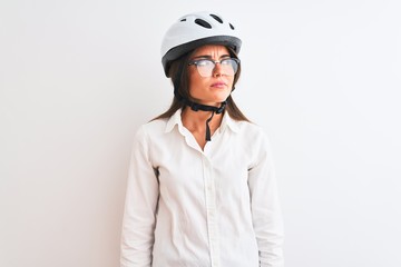 Beautiful businesswoman wearing glasses and bike helmet over isolated white background smiling looking to the side and staring away thinking.