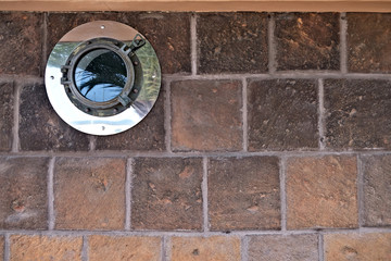 Closed decorative porthole window in a house wall, architecture abstract nautical detail.