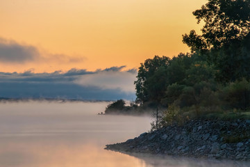Misty Morning golden sunrise across foggy river and shore nobody