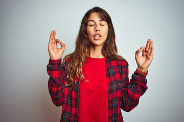 Young beautiful woman wearing red t-shirt and jacket standing over white isolated background relax and smiling with eyes closed doing meditation gesture with fingers. Yoga concept.