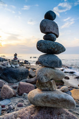 pyramid of small smooth stones by the sea against the sunset sky