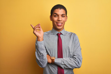 Young handsome arab businessman wearing shirt and tie over isolated yellow background with a big smile on face, pointing with hand and finger to the side looking at the camera.