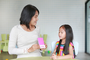 Asian mother and child girl playing flash card for Right Brain Development at the playroom. Kid learning concept.