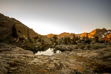 Sunrise alpenglow over still alpine lake