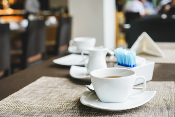 cup of hot coffee, in soft focus, on desk in restaurant with blurred people