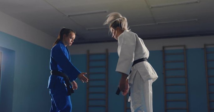 Young women work out the techniques of fighting on the tatami in the gym. Judo fighters sparring.