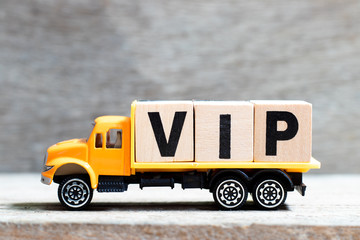 Truck hold letter block in word VIP (abbreviation of very important person) on wood background