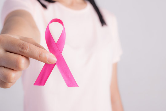 Woman holding a pink ribbon.  Breast cancer awareness month.
