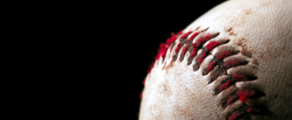Close up of old worn baseball showing dirty red stitches. Blank space for text.