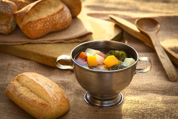 Fresh vegetarian soup made of broccoli, squash, onion, carrot, potato and tomato, photographed with natural light (Selective Focus, Focus onto the first half of the soup)