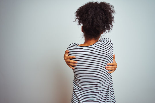African american woman wearing navy striped t-shirt standing over isolated white background Hugging oneself happy and positive from backwards. Self love and self care