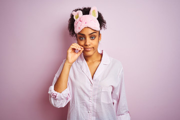 Young african american woman wearing pajama and mask over isolated pink background mouth and lips...