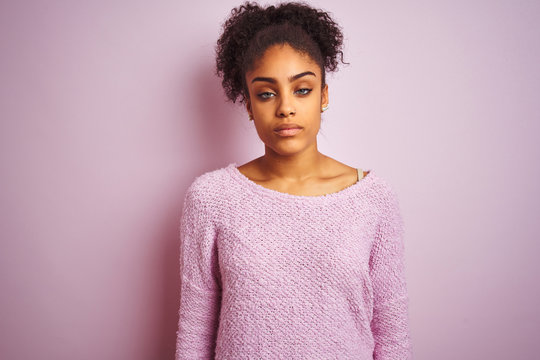 Young african american woman wearing winter sweater standing over isolated pink background looking sleepy and tired, exhausted for fatigue and hangover, lazy eyes in the morning.