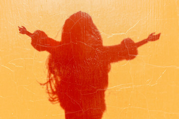 Shadow silhouette of abstract girl. Young girl spread her arms out to the light, the warmth. Minimal creative background. The concept of youth life.