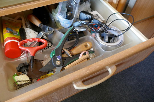 Looking into a untidy drawer.  Messy drawer with tools, household items and various other objects