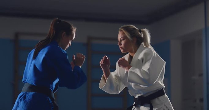 Women judoka practice tricks on the tatami in the gym. Capture, throw and painful reception.