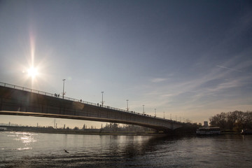 Shape of people, pedestrians, walking over brankov most (Branko's bridge), facing New belgrade, while crossing the Sava river, during a sunny sunset of winter