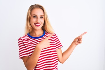 Young beautiful woman wearing red striped t-shirt standing over isolated white background smiling and looking at the camera pointing with two hands and fingers to the side.