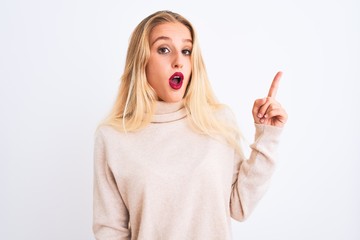 Young beautiful woman wearing turtleneck sweater standing over isolated white background pointing finger up with successful idea. Exited and happy. Number one.