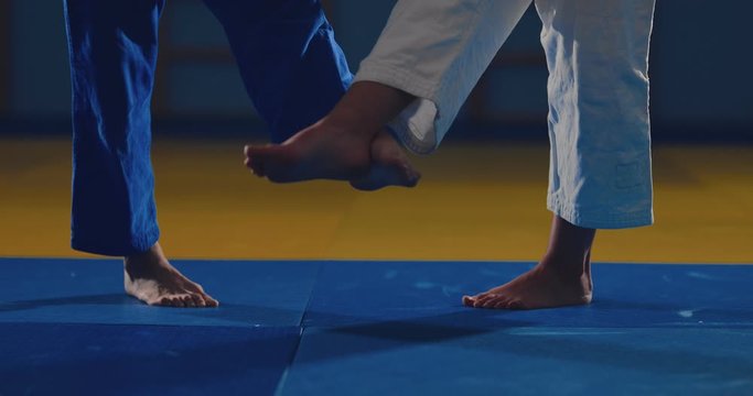 Legs of athletes on the tatami. Wrestlers make sweeps with their feet. View from below.