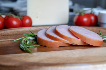Sliced Canadian Bacon with herbs served on a wooden serving trray