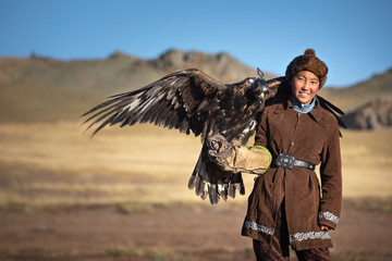 Traditional kazakh eagle huntress with her golden eagle that is used to hunt for fox and rabbit...