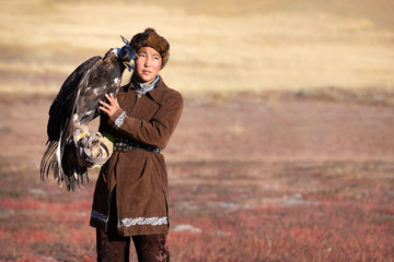 Traditional kazakh eagle huntress with her golden eagle that is used to hunt for fox and rabbit...