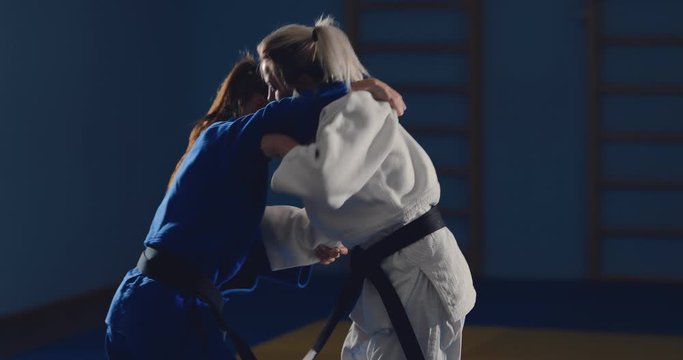 Sparing fighters, practicing techniques, throws and sweeps with their feet. Judo training.