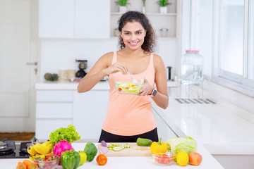 Happy Indian woman eating a bowl of tasty salad