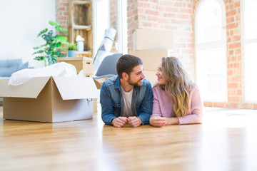 Young beautiful couple in love relaxing lying on the floor together with cardboard boxes around for moving to a new house