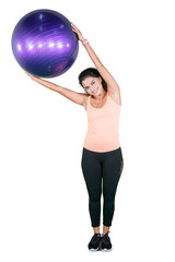 Fototapeta premium Indian woman exercising with a yoga ball on studio