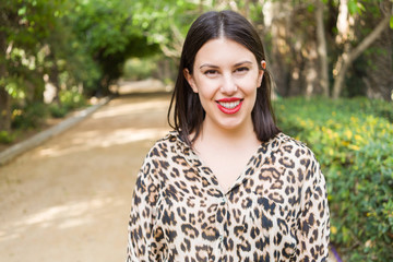 Young beautiful woman with red lips smiling happy at garden