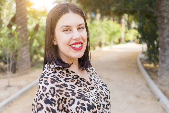 Young beautiful woman with red lips smiling happy at garden