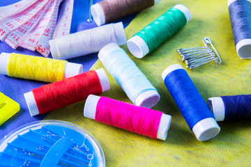Sewing tools with colorful threads above silk fabric
