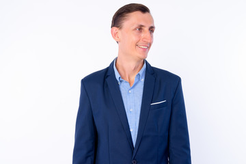 Studio shot of happy businessman in suit thinking and looking away