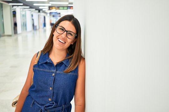 Young traveller woman at the airport going on vacation leaning on the wall