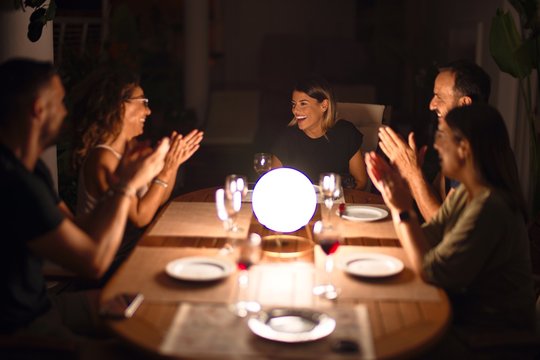 Beautiful family on dinner applauding and smiling at terrace