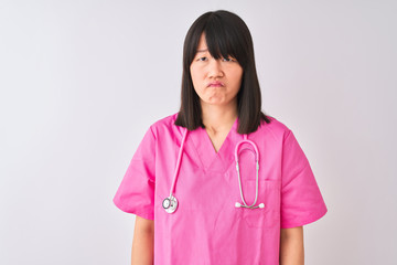 Young beautiful Chinese nurse woman wearing stethoscope over isolated white background depressed and worry for distress, crying angry and afraid. Sad expression.