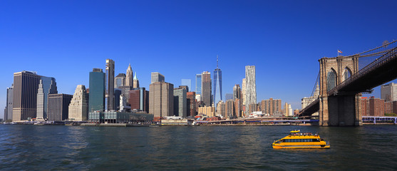 Lower Manhattan skyline, Eastern River and Brooklyn Bridge with a yellow water taxi boat on the...