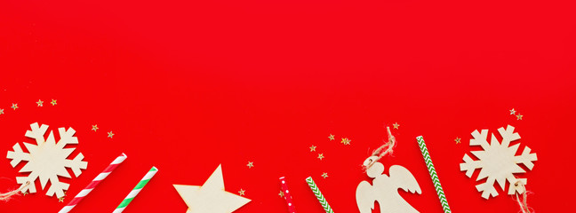 Christmas composition. Paper straws, wooden toys lying on red background. new year concept. Horizontal long banner for web design. Greeting card, winter holidays, xmas celebration 2020. Flat lay, top